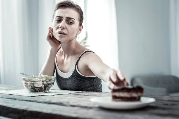 Mujer joven seria soñando con sabroso postre — Foto de Stock