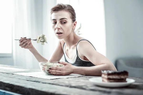 Głodny szczupła kobieta patrzy na kawałek ciasta — Zdjęcie stockowe