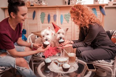Gülümseyen kadınlar doğum günü köpekleri için cupcakes veren