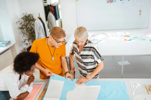 Senior vrouwelijke modeontwerper snijden een patroon — Stockfoto