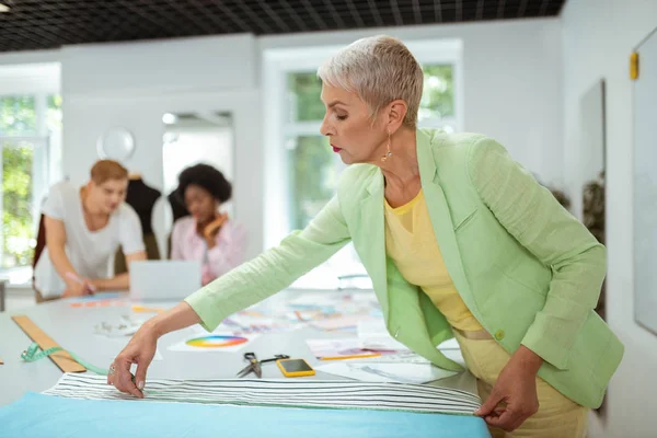 Mujer anciana diseñadora de moda trabajando en un estudio — Foto de Stock