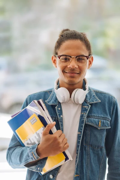 Agradable estudiante de piel oscura demostrando sus libros universitarios — Foto de Stock