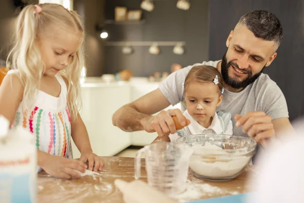 Bom homem positivo quebrando um ovo na tigela — Fotografia de Stock