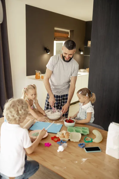 Potěšující pozitivní muž, který připravuje omeletu pro své děti — Stock fotografie