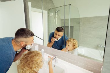 Güzel sevimli baba ve oğlu aynaya bakıyor