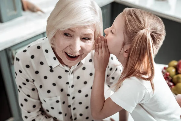 Emotionale Seniorin beeindruckt, während Enkelin Geheimnisse teilt — Stockfoto