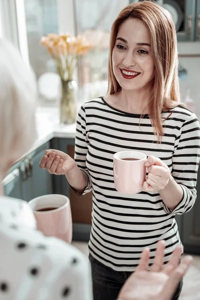 Όμορφη γυναίκα που φαίνεται χαρούμενη ενώ πίνει τσάι και έχοντας συνομιλία — Φωτογραφία Αρχείου