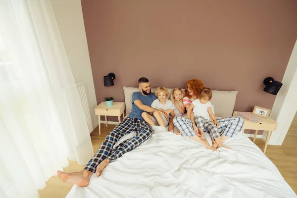 Anne-babalar yatağında yatan neşeli mutlu çocuklar — Stok fotoğraf