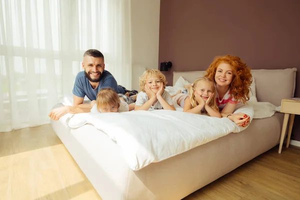 Encantada familia feliz descansando juntos en la cama — Foto de Stock