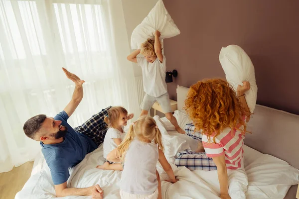 Encantada familia positiva teniendo una batalla de almohadas — Foto de Stock