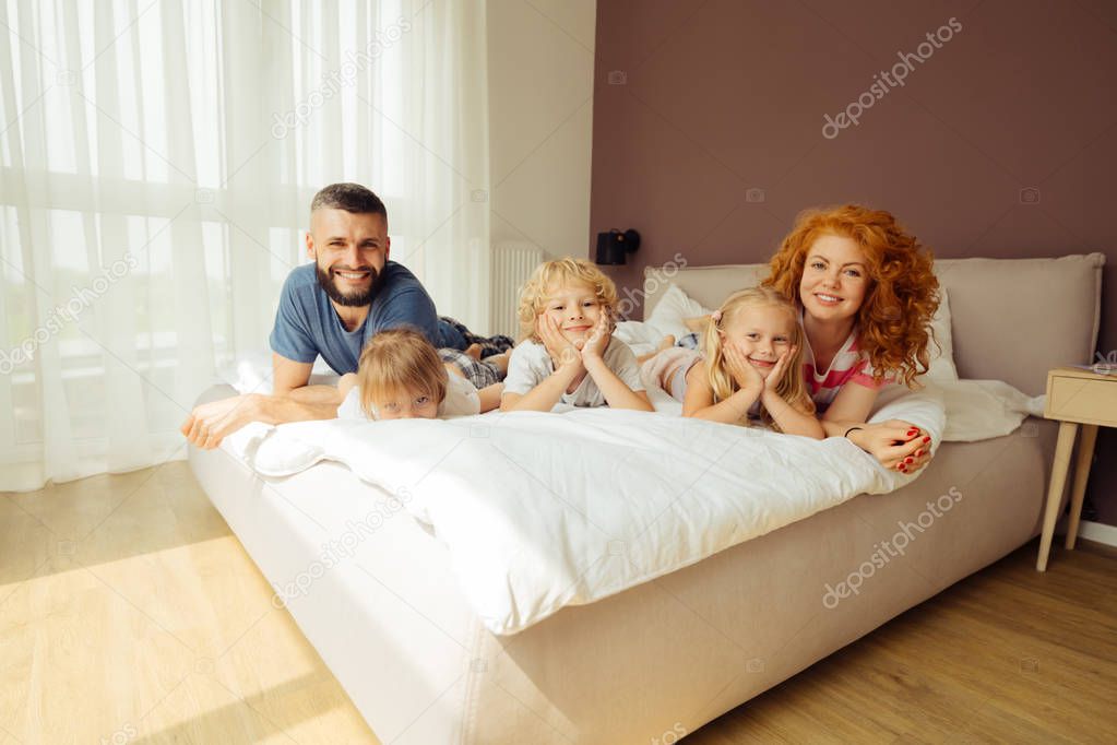 Delighted happy family resting together on the bed