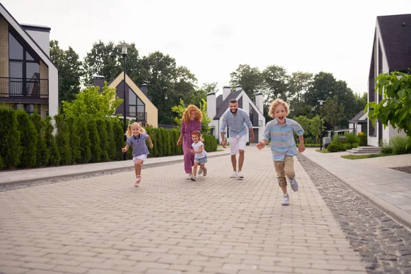 Délicieuse famille joyeuse qui court dans la rue — Photo