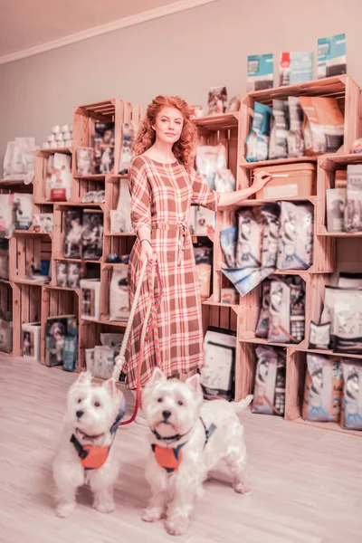 Mujer vistiendo vestido largo cuadrado de pie cerca de sus perros —  Fotos de Stock