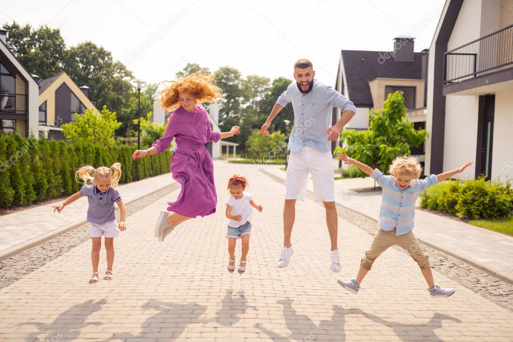 Delighted happy family jumping up on the street