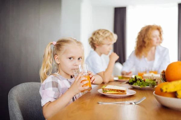 Söt blond flicka dricker färsk apelsinjuice — Stockfoto