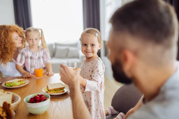 Positive süße Mädchen geben ein Glas Saft zu ihrem Vater — Stockfoto