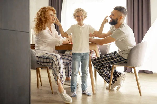 Positieve vrolijke jongen die zijn ouders neuzen aanraakt — Stockfoto