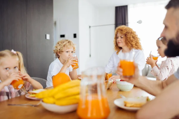 Schöne angenehme Familie trinkt Orangensaft zusammen — Stockfoto