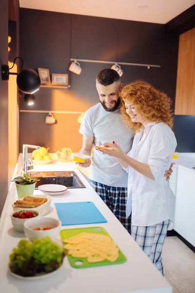 Positieve aardige vrouw die kaas op brood verspreidt — Stockfoto