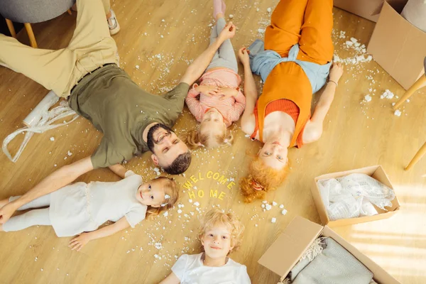 Cute delighted children lying on the floor with parents — Stock Photo, Image