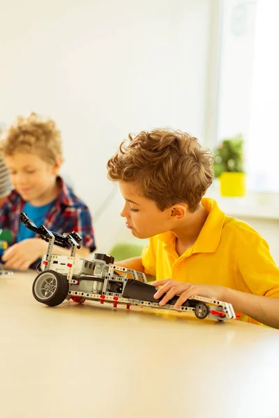 Angenehmer kleiner Junge sitzt am Schreibtisch — Stockfoto