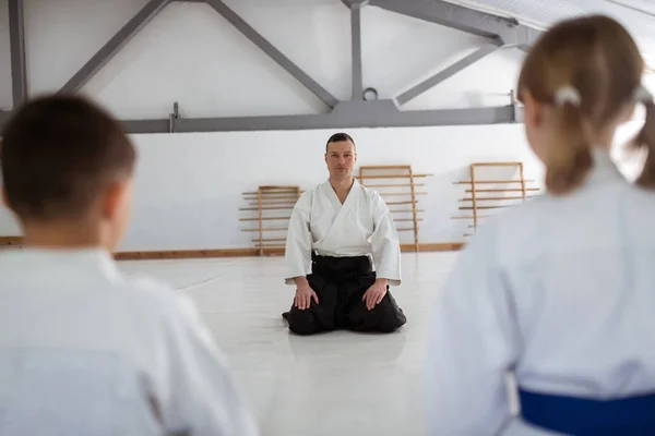 Trainer wearing black belt sitting in front of his pupils — Stock Photo, Image