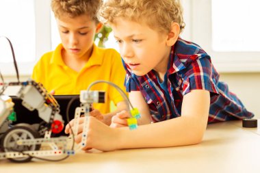 Akıllı sarışın çocuk bir robot inşa etmeye çalışıyor