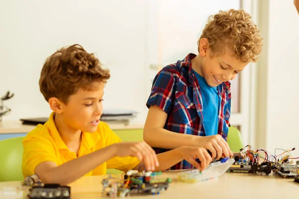 Rapazes positivos felizes construindo brinquedos diferentes juntos — Fotografia de Stock