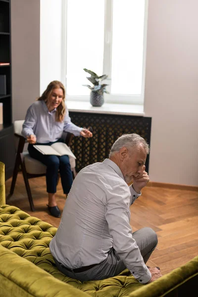 Pensive grey-haired man sitting silently on the sofa — Stock Photo, Image