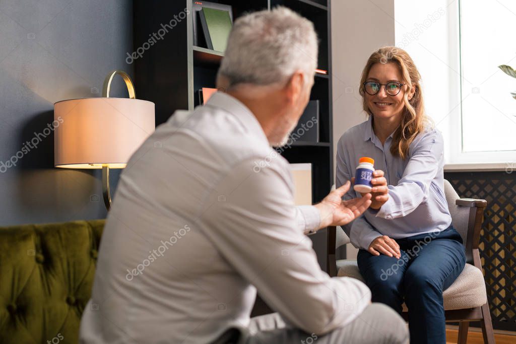 Smiling woman giving her pills to a psychotherapist
