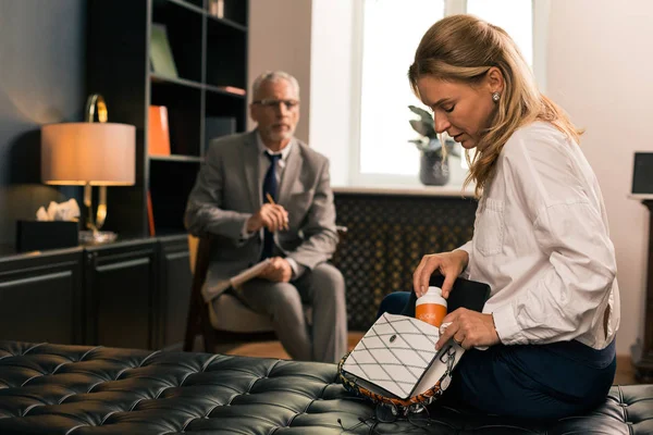 Sad patient taking pills out of her handbag — Stock Photo, Image