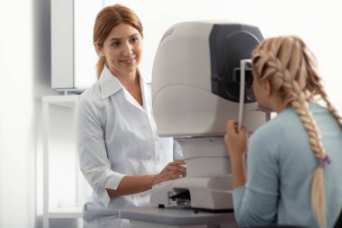 Genç kızıl saçlı göz uzmanı genç kız ile konuşuyor