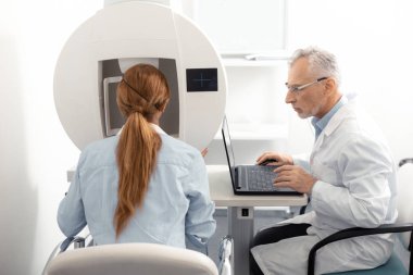 Kırmızı saçlı kadın mavi gömlek giyen göz uzmanı ziyaret