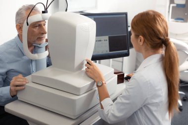 Dizüstü bilgisayarın yanında oturan beyaz üniforma giyen göz doktoru