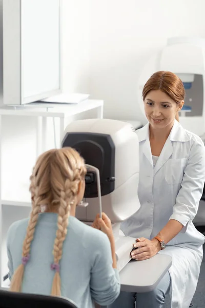 Blonde-haired girl visiting eye doctor in private clinic