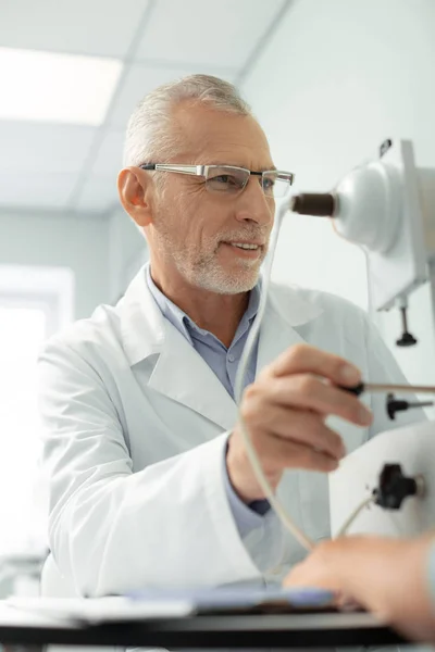 Bearded grey-haired eye specialist using modern technologies — Stock Photo, Image