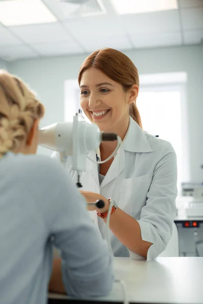 Eye doctor laughing while talking to girl during consultation