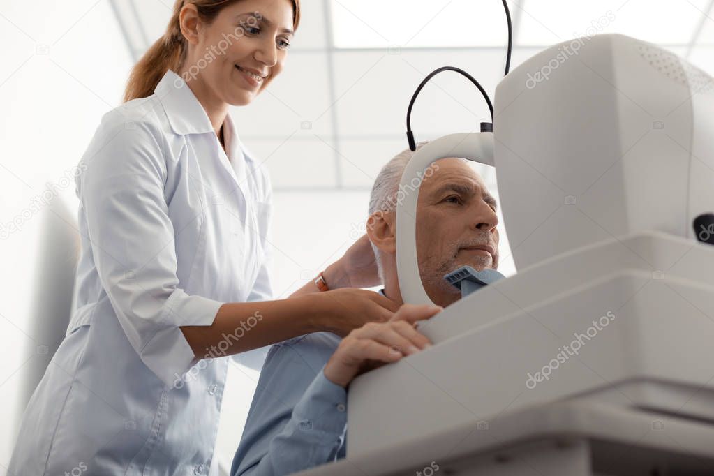 Eye specialist smiling while standing near pleasant client