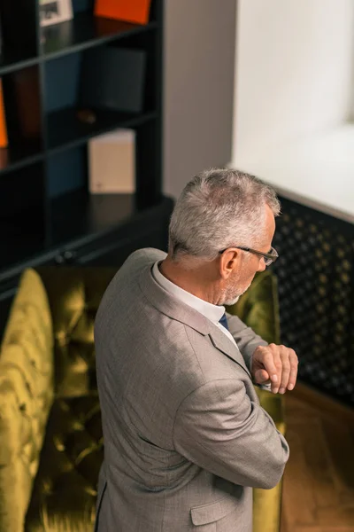 Homme aux cheveux gris portant un costume élégant regardant vers le bas — Photo