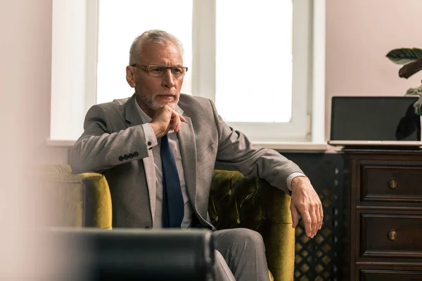 Hombre guapo sentado en un sillón verde oliva — Foto de Stock