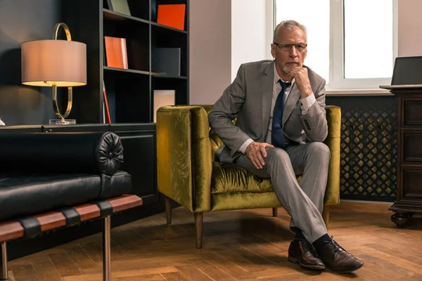 Homem sênior sério elegante sentado em seu escritório — Fotografia de Stock