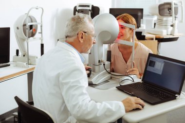 Profesyonel göz uzmanı sıkı çalışan kadın inceleyerek