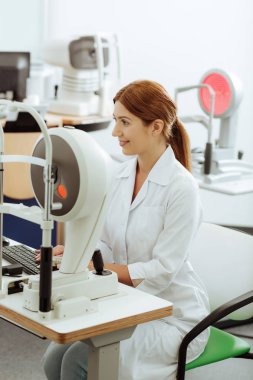 Çalışırken modern teknolojiler kullanan Kızıl saçlı göz doktoru