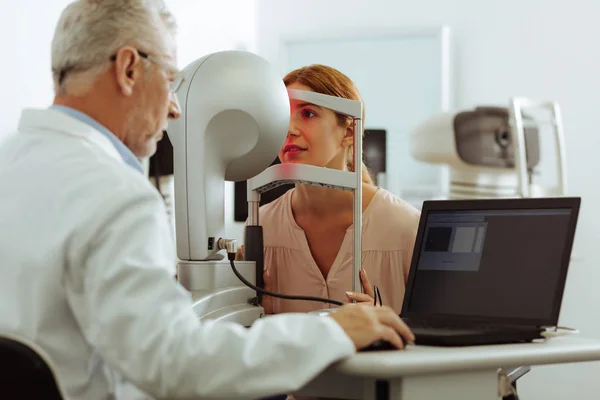 Doświadczony lekarz okulisty bada młodą kobietę — Zdjęcie stockowe