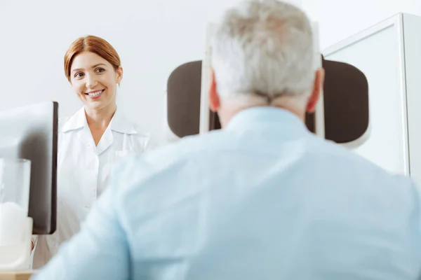 Квалифицированный офтальмолог сидит перед пациентом — стоковое фото