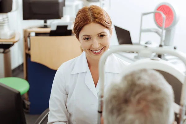 Beaming eye doctor seduto vicino al computer portatile durante la consultazione uomo — Foto Stock