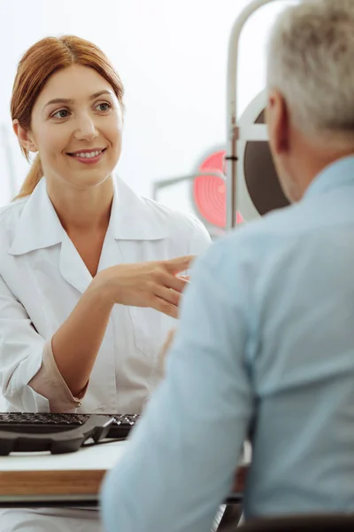 Medico oculista dai capelli rossi che controlla la vista dell'uomo in pensione — Foto Stock