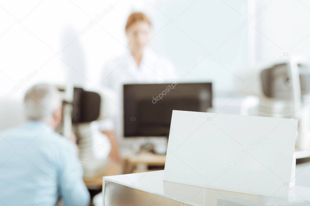 Ophthalmologist standing near laptop while examining patient