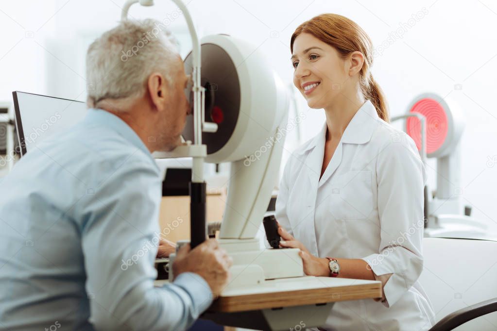 Appealing ophthalmologist smiling while working