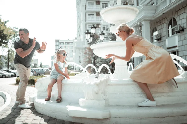 어린 소녀와 그녀의 부모는 물 튀김과 함께 연주. — 스톡 사진